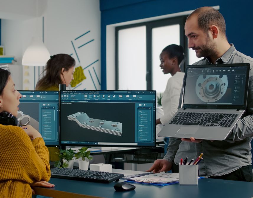 Equipo de ingenieros de Sophia Consultores colaborando en diseño mecánico CAD con computadoras y laptop en oficina moderna.